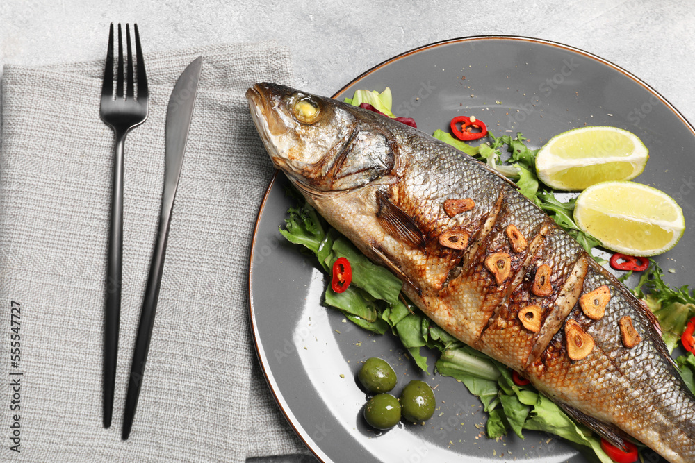 Delicious sea bass fish and ingredients served on light grey table, flat lay Delicious sea bass fish and ingredients served on light grey table, flat lay