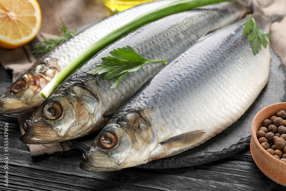 Delicious salted herrings and ingredients on black wooden table, closeup Delicious salted herrings and ingredients on black wooden table, closeup