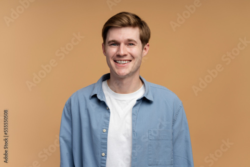 Positive successful caucasian man standing, looking at camera with happy smile