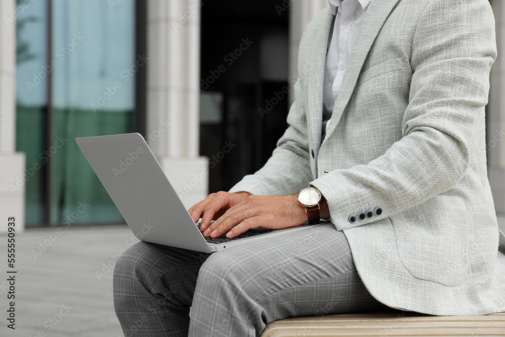Naklejka premium Businessman with laptop on city street, closeup