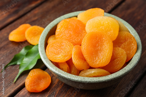 Bowl of tasty apricots on wooden table, closeup. Dried fruits