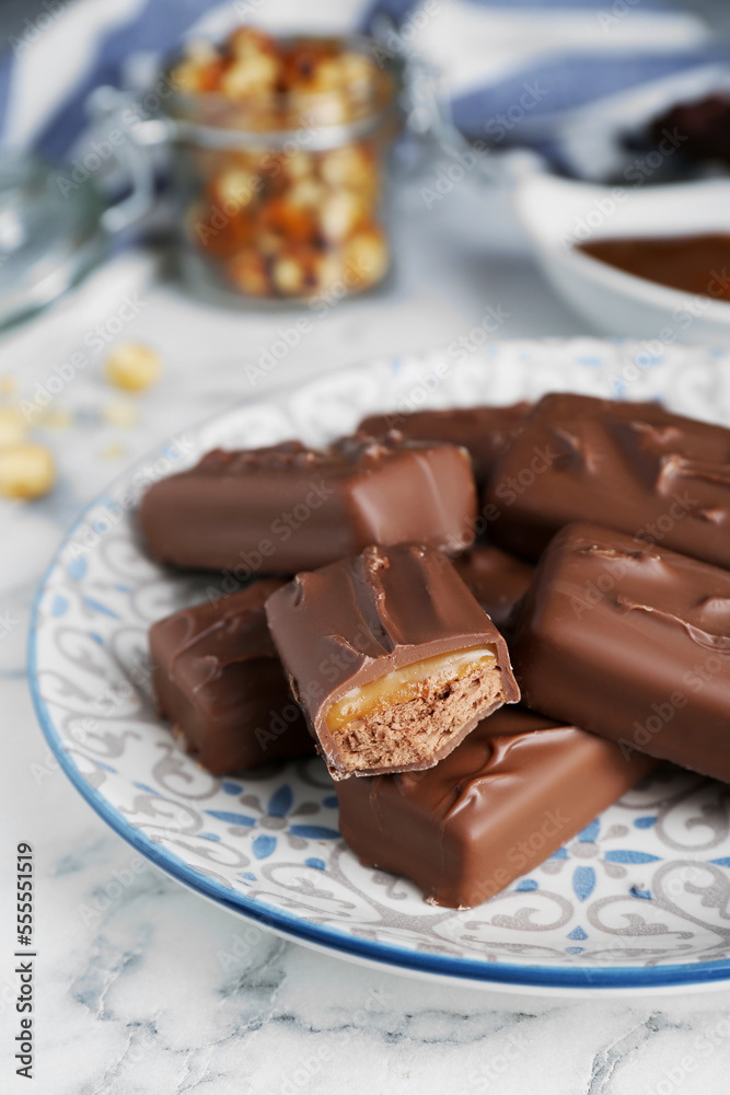 Delicious chocolate candy bars on white marble table, closeup