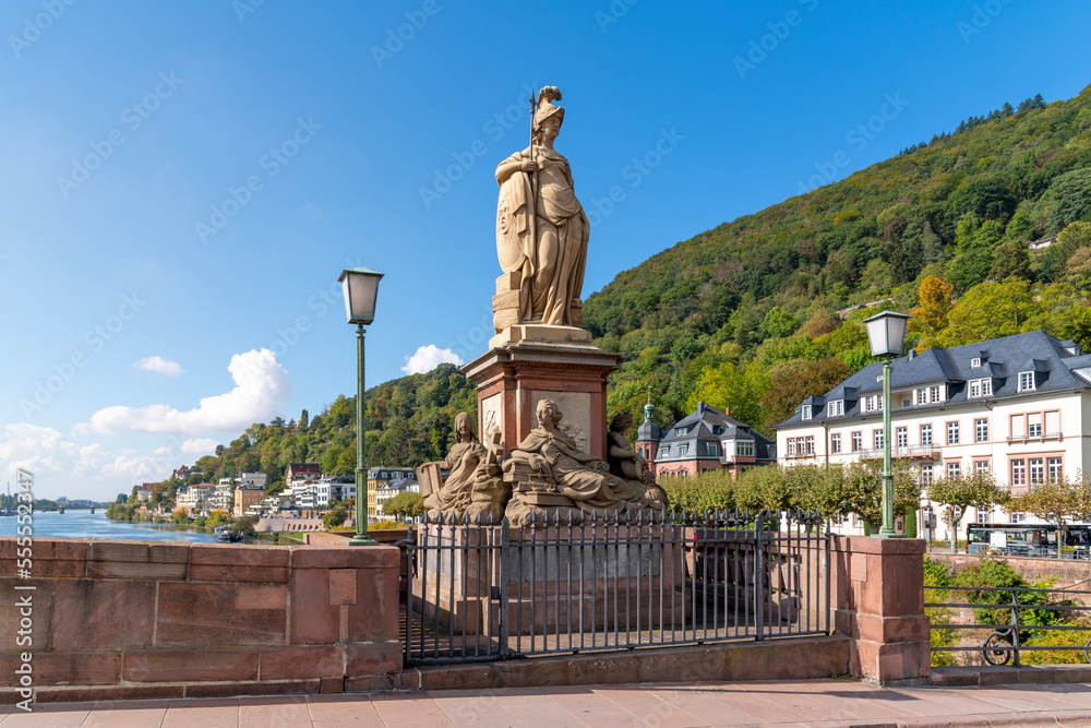 Fototapeta premium The stone statue of the goddess Minerva on a pedestal with four relief sculptures at the base, on the Karl Theodor Old Bridge in Heidelberg, Germany.