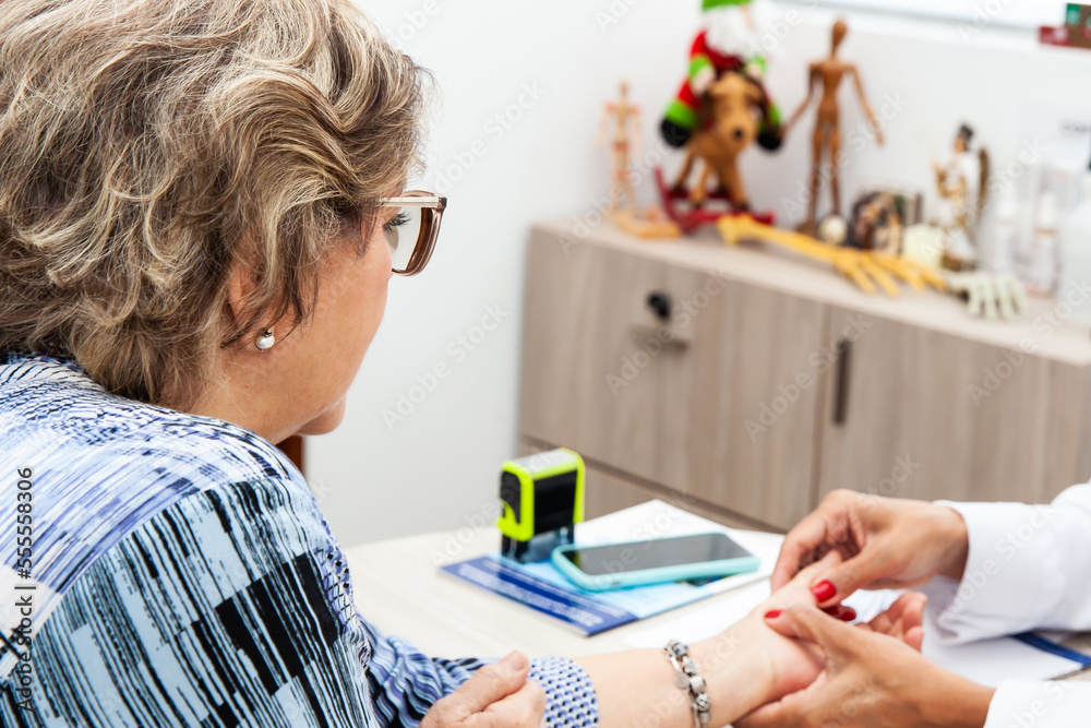 Senior female patient in consultation with a traumatologist female doctor. Skeleton bone disease exam and medic aid. Insurance concept