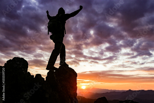 Asian man looking at mountain on cliff and success