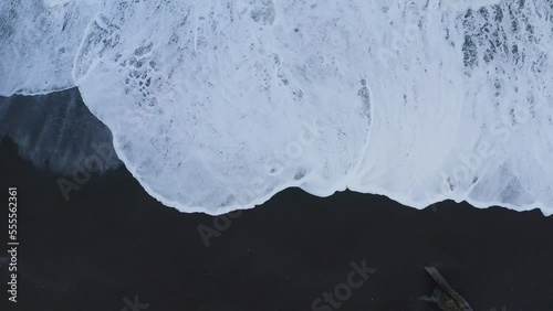 Aerial top down shot of foamy waves reaching black sandy beach in Iceland photo