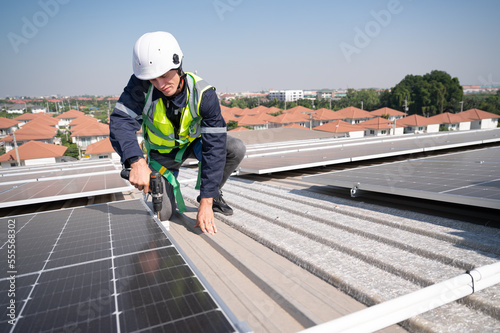 Caucasian engineer man use electric screwdriver working with solar panel on roof factory