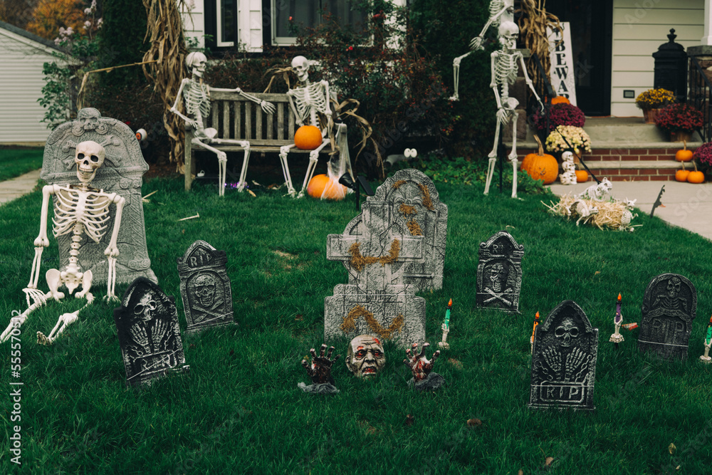 Φωτογραφία Many bright and colorful inflatable Halloween decorations, skeletons, carved pumpkins, and scarecrows in the driveway and front lawns of a residential house