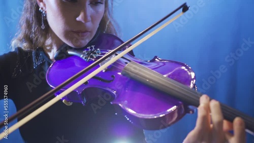 The female violinist plays the violin at the music school, the musician plays the violin at the opera.