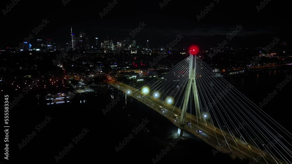 Aerial panoramic shot of Warsaw cityscape. Swietokrzyski suspension bridge over Vistula river, skyscrapers downtown urban skyline at night. Cinematic city panorama flyover cable bridge towers Aerial panoramic shot of Warsaw cityscape. Swietokrzyski suspension bridge over Vistula river, skyscrapers downtown urban skyline at night. Cinematic city panorama flyover cable bridge towers