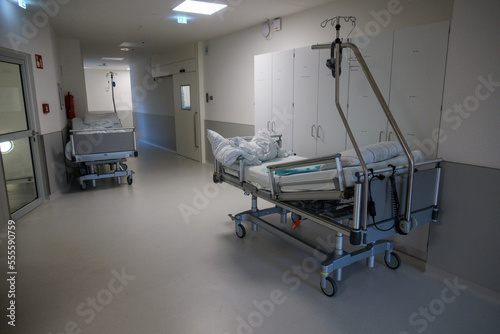 in a hospital corridor there is an empty bed