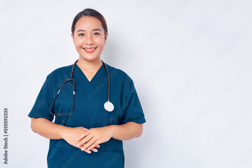 Smiling young Asian woman nurse wearing blue uniform with a stethoscope looking ready to help and listening to a patient isolated on white background. Healthcare medicine concept Smiling young Asian woman nurse wearing blue uniform with a stethoscope looking ready to help and listening to a patient isolated on white background. Healthcare medicine concept