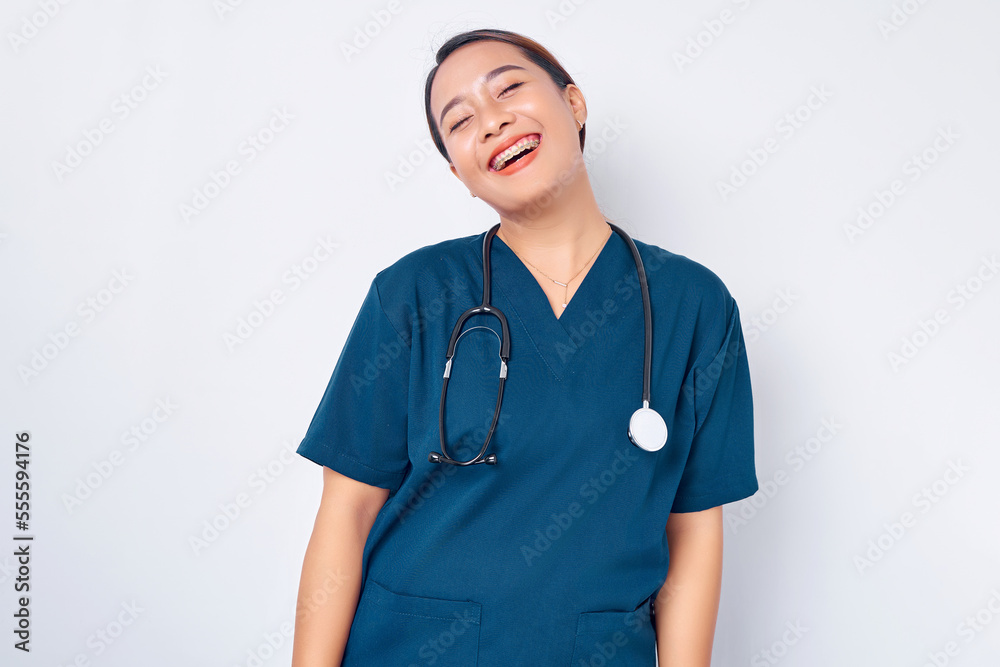 Carefree young Asian woman nurse wearing blue uniform with a stethoscope intern having fun, laughing happy, lunch break chuckle isolated on white background. Healthcare medicine concept Carefree young Asian woman nurse wearing blue uniform with a stethoscope intern having fun, laughing happy, lunch break chuckle isolated on white background. Healthcare medicine concept