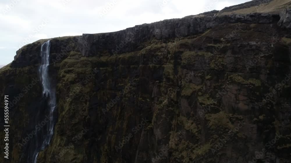 drone shot of waterfall comming in frame on top of stone mountains in Iceland drone shot of waterfall comming in frame on top of stone mountains in Iceland