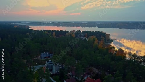 Wallpaper Mural Aerial drone shot over wooden houses beside a large lake along rural countryside surrounded by dense green vegetation during evening time. Torontodigital.ca