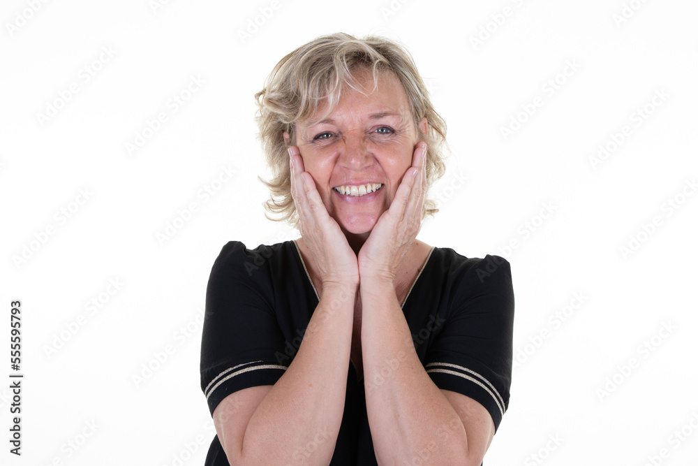 Smiling blonde mature woman with head hands on cheeks in white studio background Smiling blonde mature woman with head hands on cheeks in white studio background