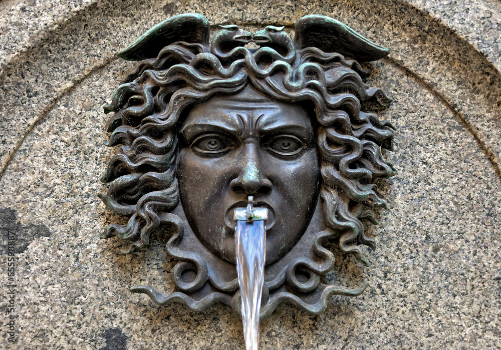 detail of historic fountain, part of Escalade Fountain on crossing of Rue de la Cite and Rue de la Confederation, bronze Medusa's head, dated 1857, old town of Geneva, Switzerland, Europe