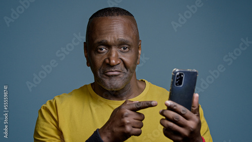 Foto Mature man standing in studio on gray background holding mobile phone browsing s