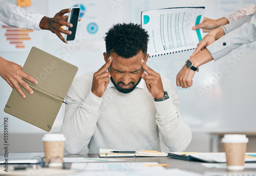 Stress, burnout and tired black man with headache, frustrated or overwhelmed by coworkers at workplace. Overworked, mental health and anxiety of exhausted male worker multitasking at desk in office.