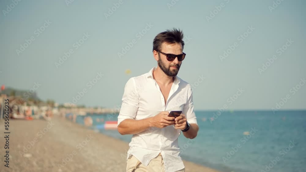 The freelancer is working remotely on the seacoast beach using their mobile phone The freelancer is working remotely on the seacoast beach using their mobile phone