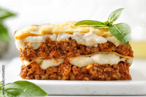 Lasagna. Homemade Italian Lasagne with bolognese meat sauce, bechamel, cheese and basil on white board.