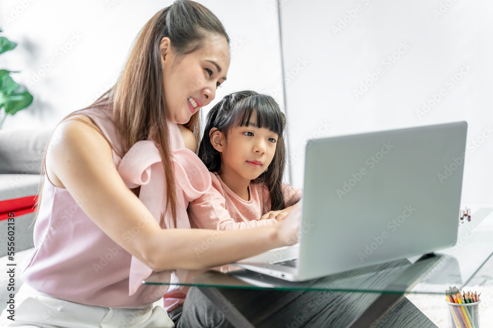 Asian family portrait, father and daughter in the living room The daughter did her homework with her mother, giving advice and teaching closely. Asian family portrait, father and daughter in the living room The daughter did her homework with her mother, giving advice and teaching closely.