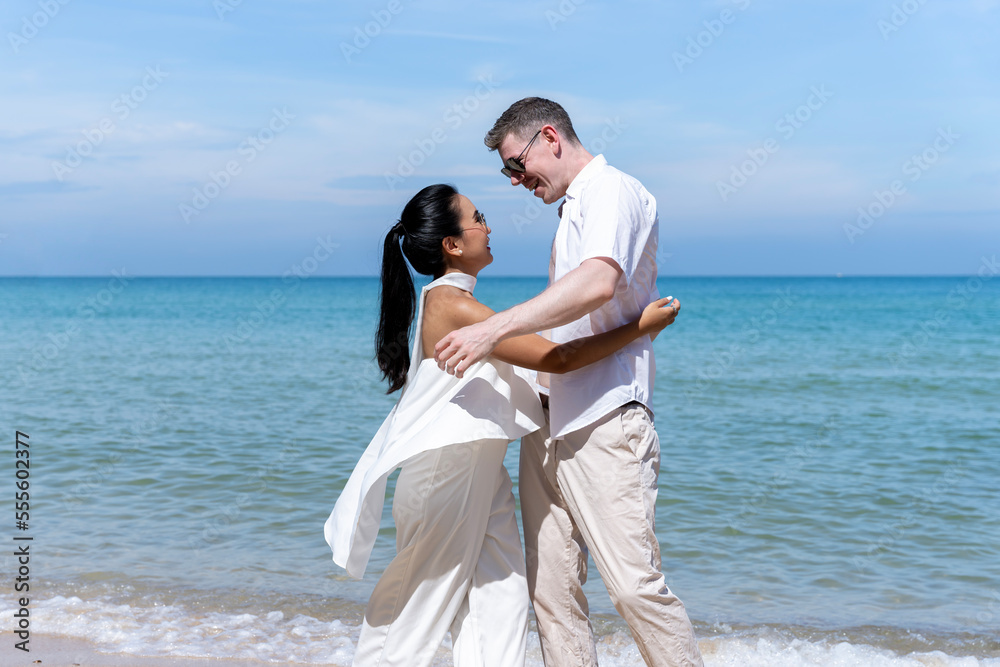 A couple of men and women of different nationalities go to the beach and walk happily on the beach together. on summer vacation A couple of men and women of different nationalities go to the beach and walk happily on the beach together. on summer vacation