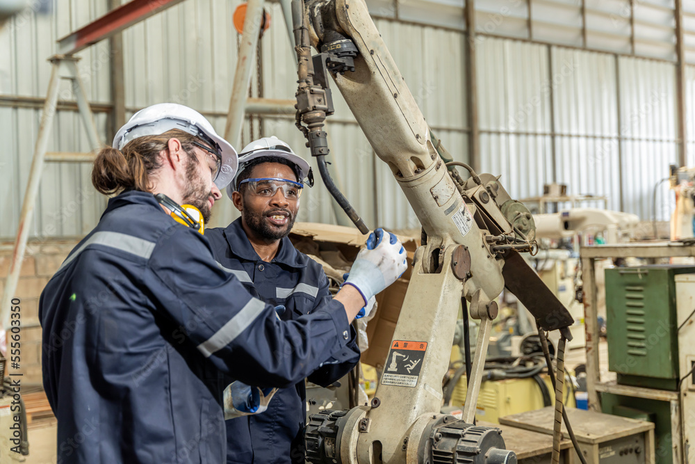 A team of male and female engineers meeting to inspect computer-controlled steel welding robots. Plan for rehearsals and installation for use. A team of male and female engineers meeting to inspect computer-controlled steel welding robots. Plan for rehearsals and installation for use.