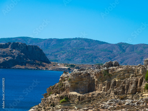 Panoramic view of the Mediterranean Sea on the rocky coast. Mountain range with clear turquoise water and blue sky. Located near Stegna, Archangelos, Rhodes, Dodecanese Islands, Greece photo