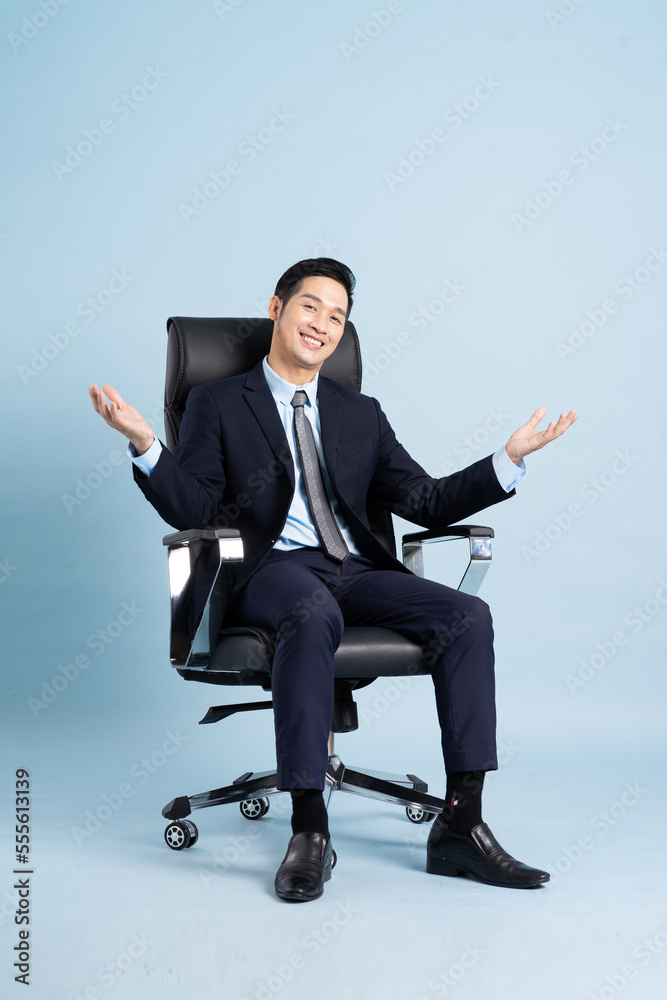 Asian businessman male portrait sitting on chair and isolated on blue background Asian businessman male portrait sitting on chair and isolated on blue background