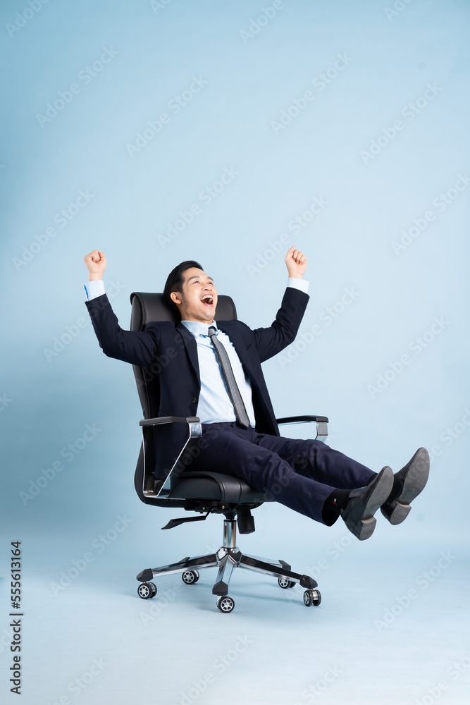 Asian businessman male portrait sitting on chair and isolated on blue background Asian businessman male portrait sitting on chair and isolated on blue background