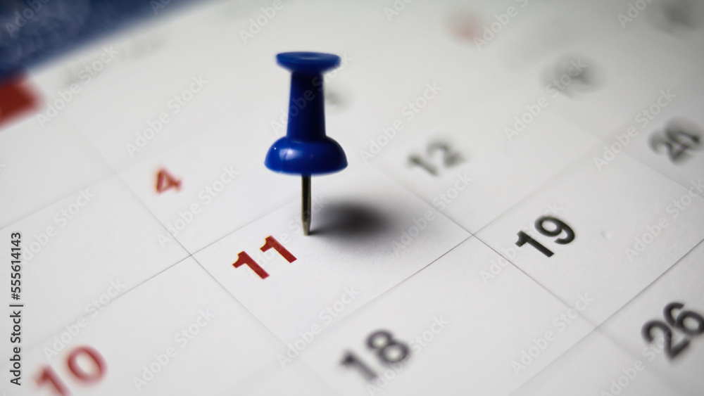 Embroidered red pins on a calendar on the 11 th with selective focus Embroidered red pins on a calendar on the 11 th with selective focus