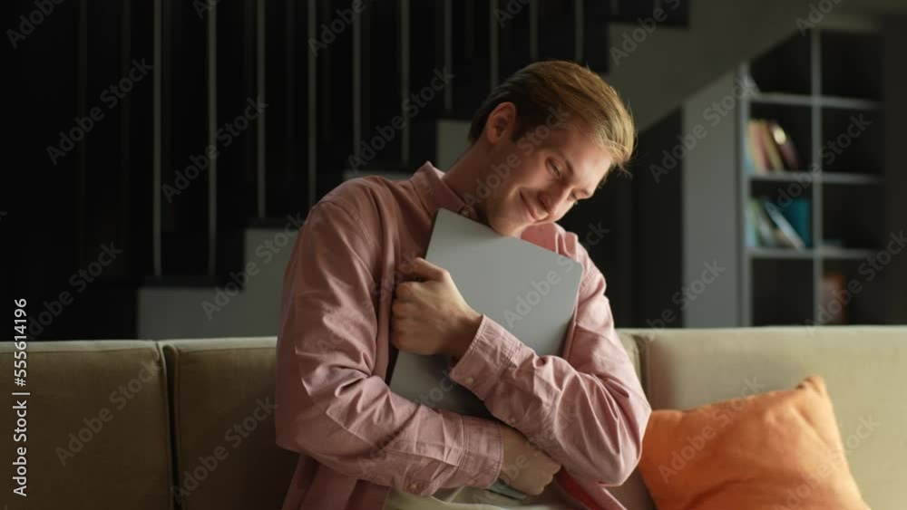 Ufa, Russia - 10 October 2022. Portrait of happy satisfied young man hugging new Apple MacBook Pro 16 inch closed eyes sitting on couch at table sunny in living room. Online shopping concept. Shooting Ufa, Russia - 10 October 2022. Portrait of happy satisfied young man hugging new Apple MacBook Pro 16 inch closed eyes sitting on couch at table sunny in living room. Online shopping concept. Shooting