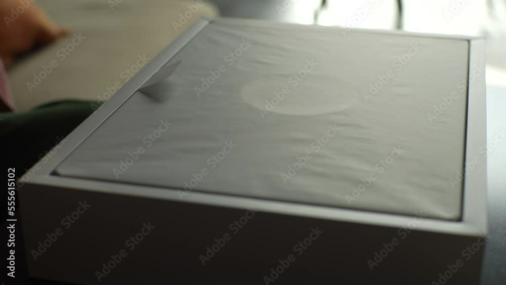 Ufa, Russia - 10 October 2022. Close-up hands of unrecognizable happy young man unpacking latest cardboard box Apple MacBook Pro 16 inch sitting on sofa at desk in sunny living room. Online shopping