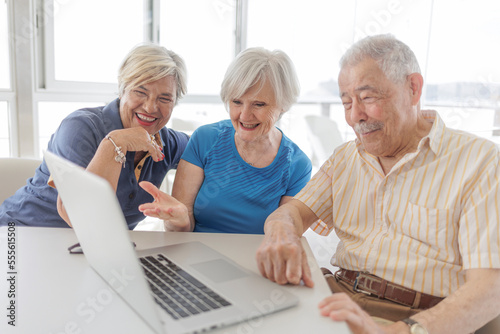 tre anziani fanno una videochiamata attraverso il computer portatile seduti in un bar 