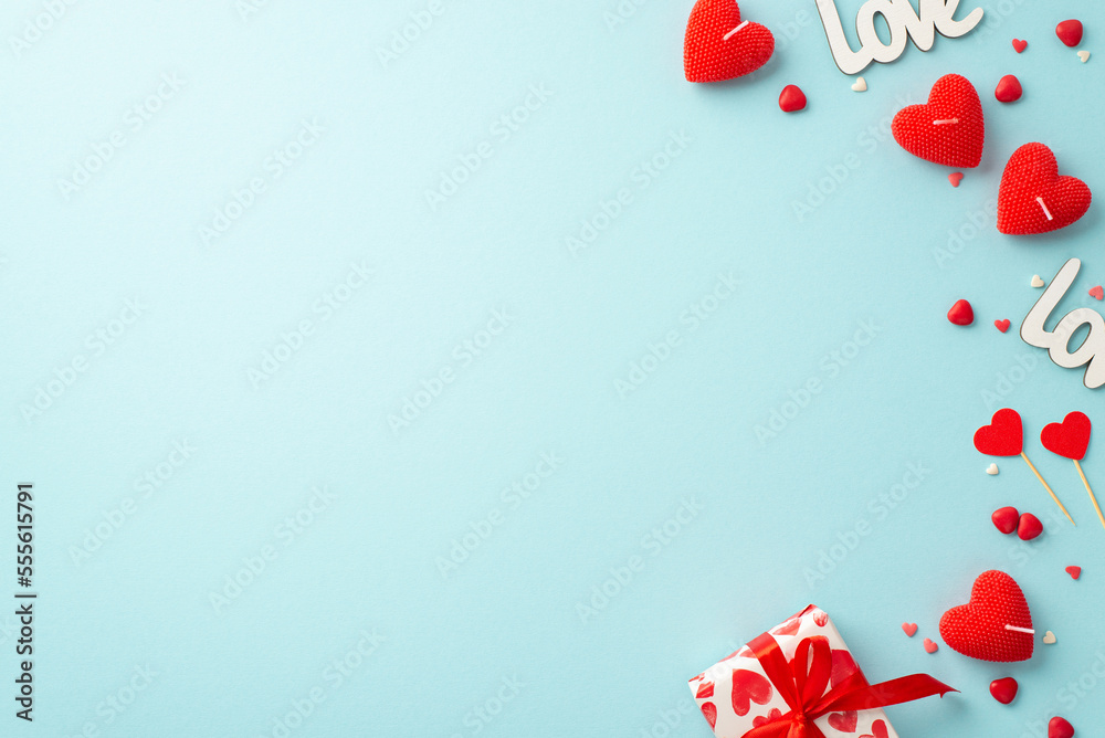 St Valentine's Day concept. Top view photo of heart shaped candles inscriptions love small giftbox and sprinkles on isolated pastel blue background with copyspace St Valentine's Day concept. Top view photo of heart shaped candles inscriptions love small giftbox and sprinkles on isolated pastel blue background with copyspace
