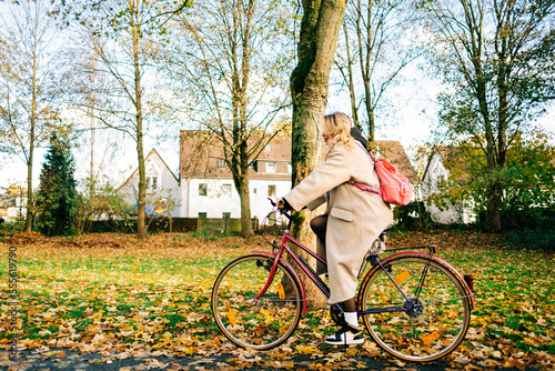 Young attractive caucasian woman ride on bicycle in the park on warm day in the fall.