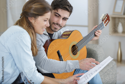 man playing guitar and woman holding sheet music