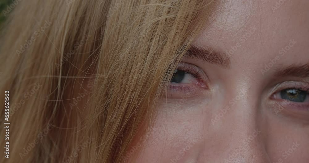 Extreme close-up of big blue eyes of an attractive blonde girl looking at the camera and smiling. Concept of ophthalmology and eye fatigue Extreme close-up of big blue eyes of an attractive blonde girl looking at the camera and smiling. Concept of ophthalmology and eye fatigue