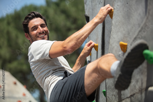handsome young man bouldering or rock climbing outdoors