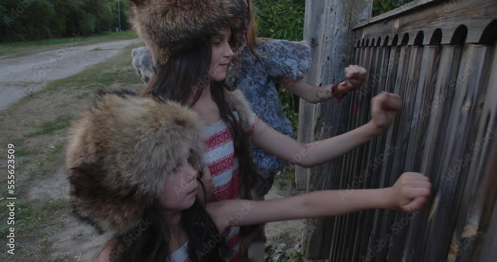 Group of three girls dressed in strange  fur suits, knocking on wooden door of rural house. 