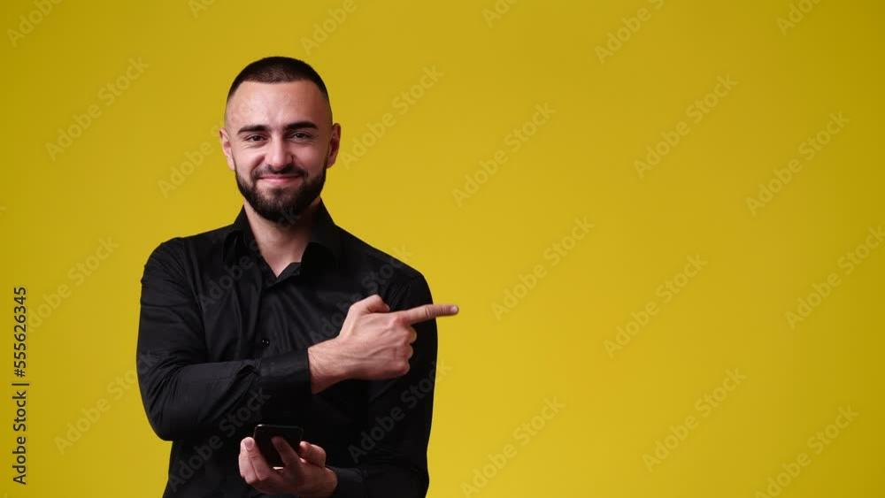 4k slow motion video of man using phone and pointing at right side over yellow background. 4k slow motion video of man using phone and pointing at right side over yellow background.