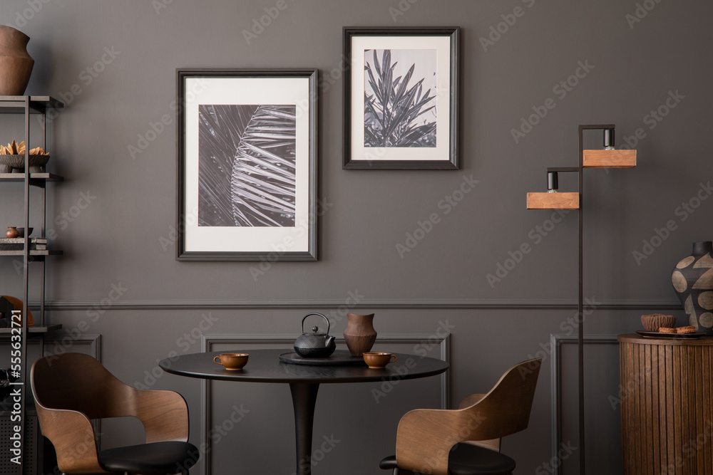 Fototapeta premium Interior design of living room interior with mock up posters frames, round table, wooden xhair, dark wall with stucco, glass, trace and personal accessories. Home decor. Template.
