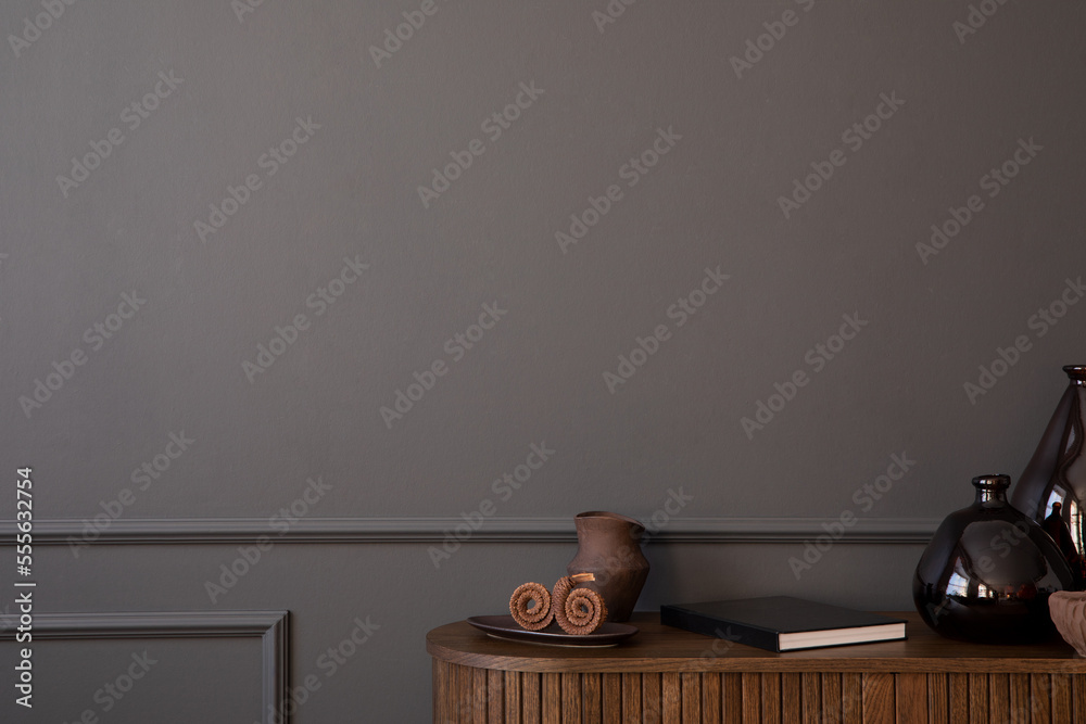 Minimalist composition of living room interior with copy space, dark wall with stucco, wooden sideboard, glass vase, book, bowl and personal accessories. Home decor. Template. Minimalist composition of living room interior with copy space, dark wall with stucco, wooden sideboard, glass vase, book, bowl and personal accessories. Home decor. Template.