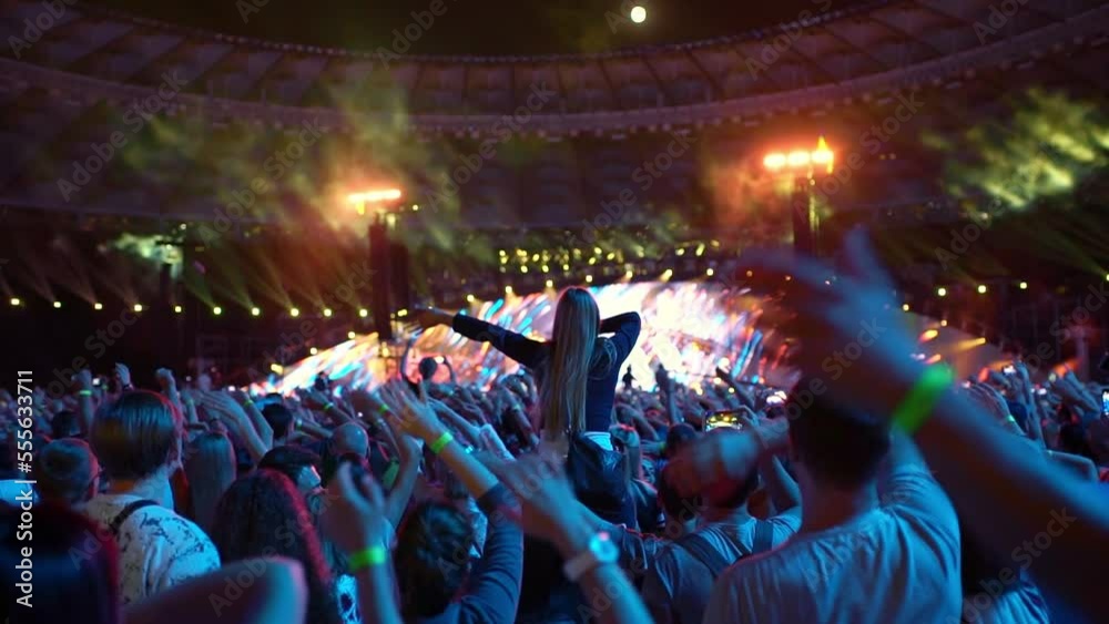 Fans applaud in front of the stage at a concert.