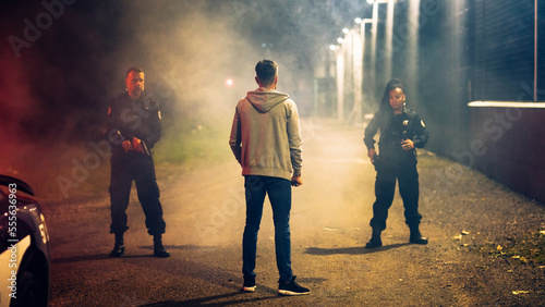 Two Police Officers Catch and Arrest Suspect. Heroic Officers of the Law Tackle and Stop Dangerous Criminal on the Dark City Street. Cops Arresting Felon, Fight Crime. Dramatic Cinematic Shot