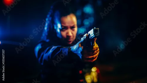 Obraz Portrait of Black Female Police Officer Aiming Gun at Criminal, Orders to Drop the Weapon and Stop Resisting Arrest. Officer of the Law Fights Crime, Prevents Murder. Cinematic