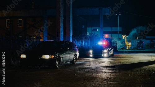 Highway Traffic Patrol Car In Pursuit of Criminal Vehicle, Traffic Stop, Pull Over, Arrest. Police Officer Gets out of Squad Car, Approaches Suspect. Cinematic Action in Industrial Urban Area at Night