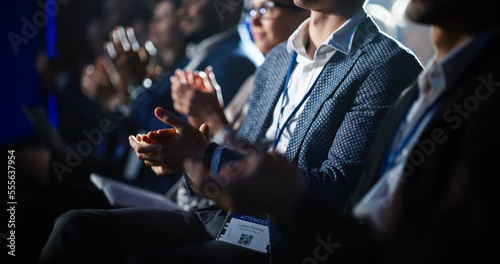 Close Up on Hands of a Crowd of People Clapping in Dark Conference Hall During a Motivational Keynote Presentation. Business Technology Summit Auditorium Room Full of Delegates. photo
