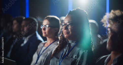 Portrait of a Beautiful Black Female Sitting in a Dark Crowded Auditorium at a Tech Conference. African Woman Listening to an Inspiring Keynote Presentation. Specialist Interested in New Technology.